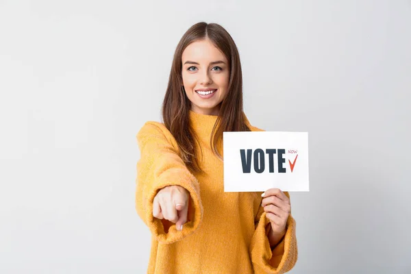 Young woman holding paper with text VOTE on light background — Stock Photo, Image