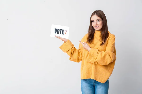 Jovem segurando papel com texto VOTE no fundo claro — Fotografia de Stock