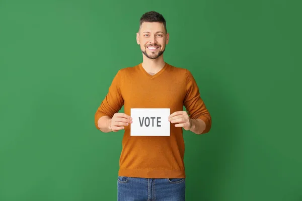 Mężczyzna trzyma papier z tekstem Głosuj na tle koloru — Zdjęcie stockowe