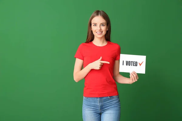 Young woman holding paper with text I VOTED on color background — Stock Photo, Image