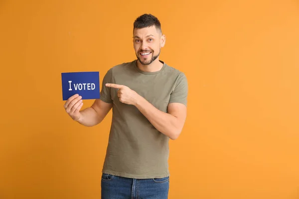 Man holding paper with text I VOTED on color background — Stock Photo, Image