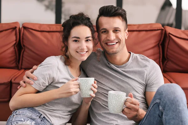 Feliz joven pareja bebiendo té en casa — Foto de Stock