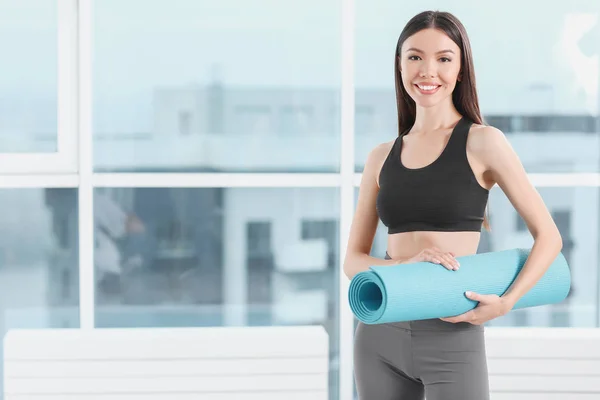 Sportliche junge Frau mit Yogamatte im Fitnessstudio — Stockfoto