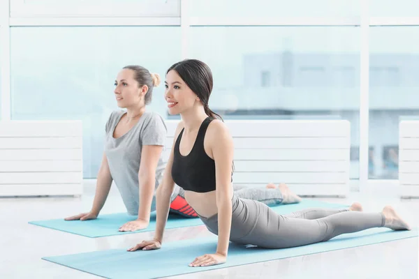Mujeres jóvenes deportistas practicando yoga en el gimnasio — Foto de Stock