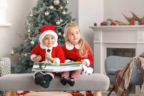 Cute małe dzieci w kostiumach Santa i z książki w domu w Wigilię Bożego Narodzenia — Zdjęcie stockowe