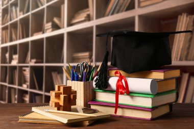 Havan tahtası, diploma, kırtasiye ve kütüphanedeki masanın üzerinde kitaplar.