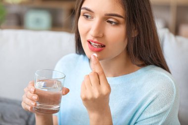 Evde ilaç alan genç bir kadın.