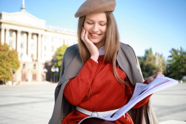 Dışarıda gazetesi olan genç bir kadın.