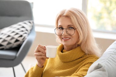 Güzel olgun kadın evde kahve içiyor.