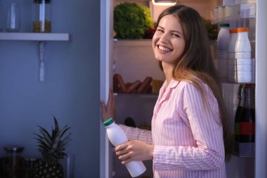 Güzel genç kadın geceleri Buzdolabında yemek seçimi