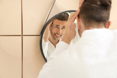 Banyoda aynanın yanında yakışıklı bir adam.