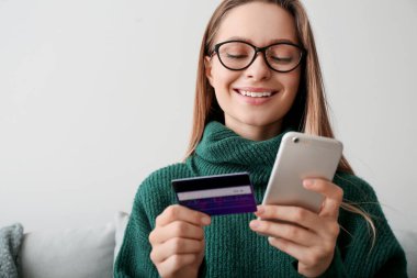 Kredi kartı ve cep telefonu alışverişi yapan genç bir kadın.