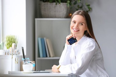 Kredi kartı ve bilgisayar alışverişi yapan genç bir kadın.