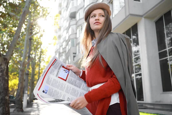 Ung kvinna med tidning utomhus — Stockfoto