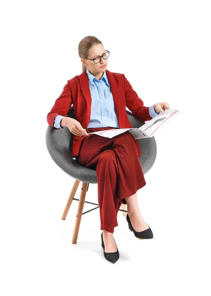 Young businesswoman with newspaper sitting in armchair against white background — Stock Photo, Image