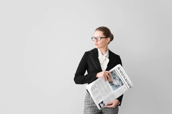 Young businesswoman with newspaper on light background — Stock Photo, Image