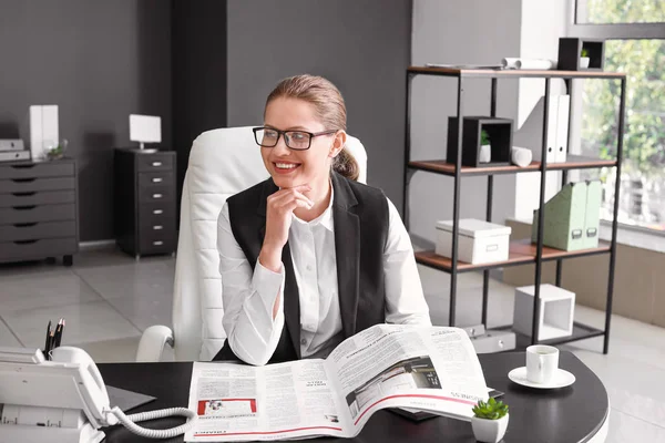 Young businesswoman reading newspaper in office — Stock Photo, Image