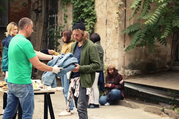 Voluntarios dando ropa y comida a personas sin hogar al aire libre —  Fotos de Stock