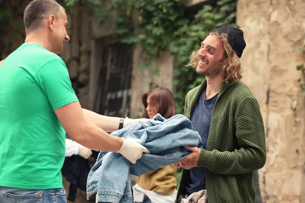 Voluntarios dando ropa a personas sin hogar al aire libre —  Fotos de Stock