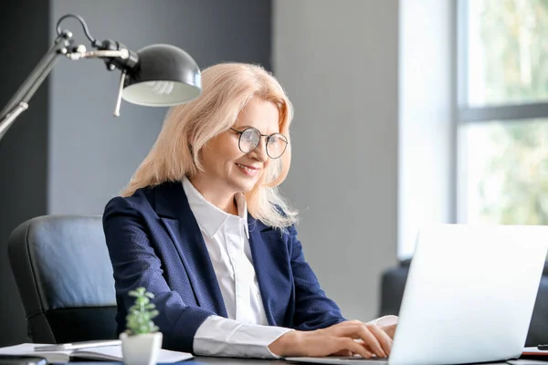 Mature businesswoman working on laptop in office — Stock Photo, Image