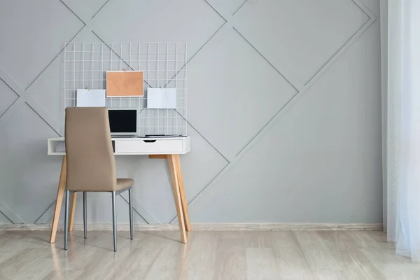 Stylish workplace with laptop near grey wall — Stock Photo, Image