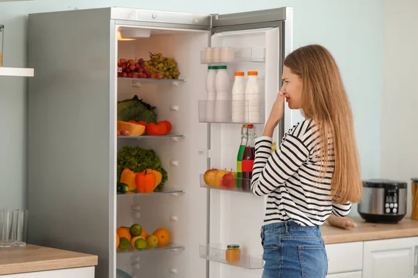 Frau verspürt schlechten Geruch aus Kühlschrank in Küche — Stockfoto