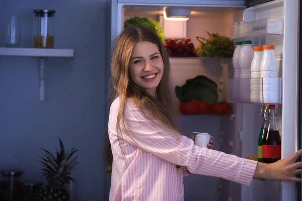 Schöne junge Frau bei der Wahl von Lebensmitteln im Kühlschrank nachts — Stockfoto
