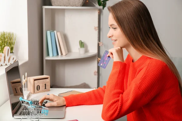 Ung kvinna med kreditkort och dator shopping online hemma — Stockfoto