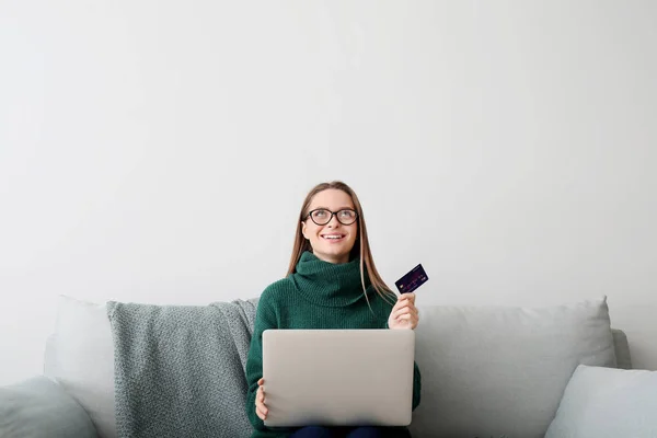 Ung kvinna med kreditkort och dator shopping online hemma — Stockfoto