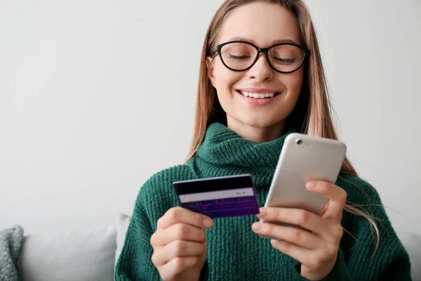 Молодая женщина с кредитной картой и мобильного телефона покупки в Интернете дома — стоковое фото