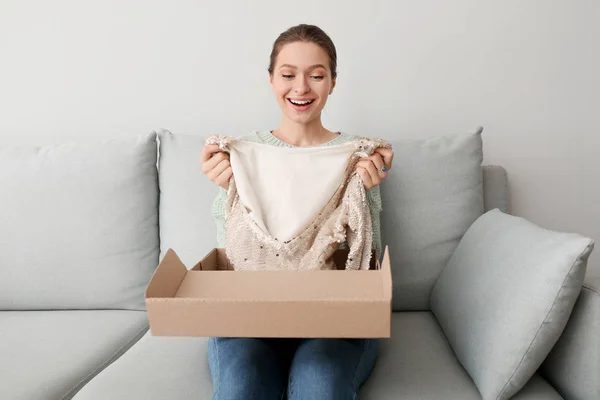 Happy young woman with received new clothes at home — Stock Photo, Image