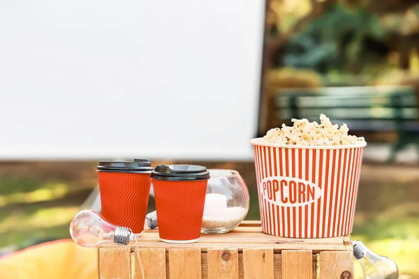 Bucket of popcorn with tasty coffee in outdoor cinema — Stock Photo, Image