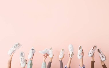 Renkli arka planda farklı şık ayakkabıları olan birçok el