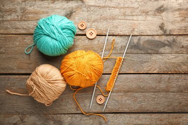 Ahşap arka planda örgü iplikleri ve iğneler.
