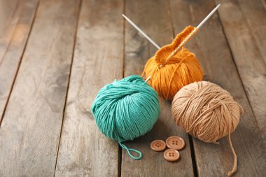 Ahşap arka planda örgü iplikleri ve iğneler.