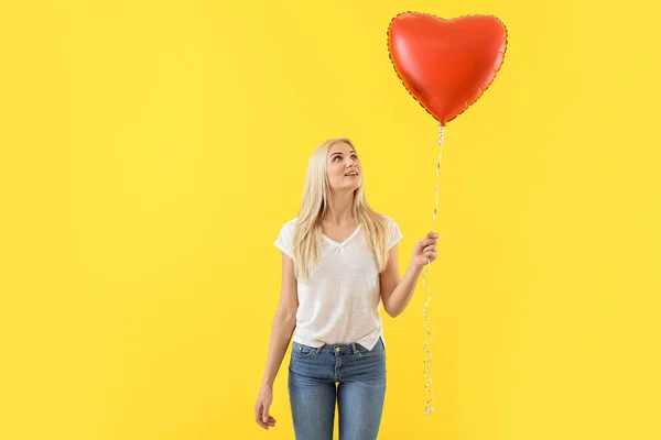Beautiful young woman with heart-shaped balloon on color background — Stock Photo, Image