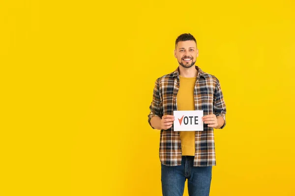 Man holding paper with text VOTE on color background — Stock Photo, Image