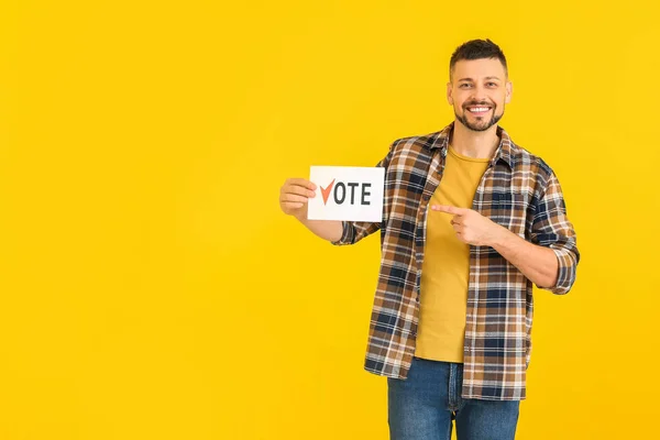 Man holding paper with text VOTE on color background — Stock Photo, Image