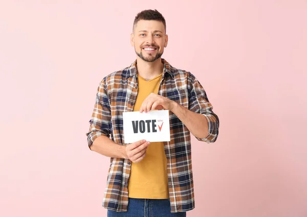Mężczyzna trzyma papier z tekstem Głosuj na tle koloru — Zdjęcie stockowe