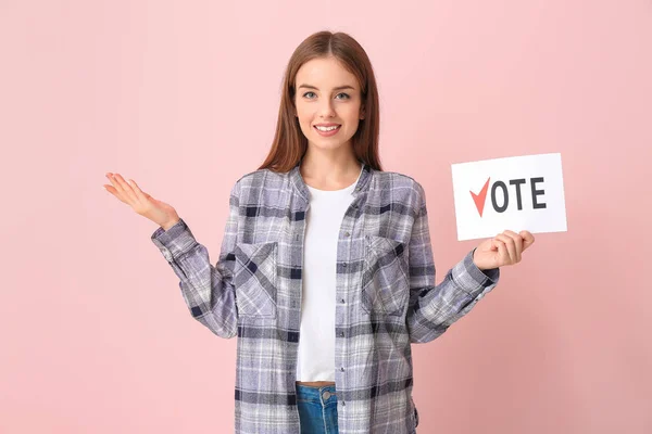 Молодая женщина держит бумагу с текстом VOTE на цветном фоне — стоковое фото