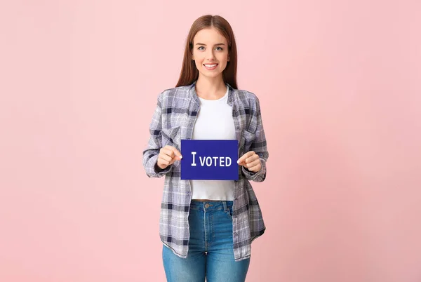 Молода жінка тримає папір з текстом I VOTED на кольоровому фоні — стокове фото