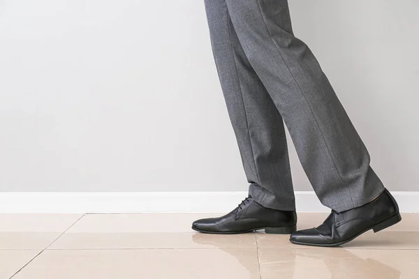 Hombre joven en zapatos elegantes cerca de la pared de luz — Foto de Stock