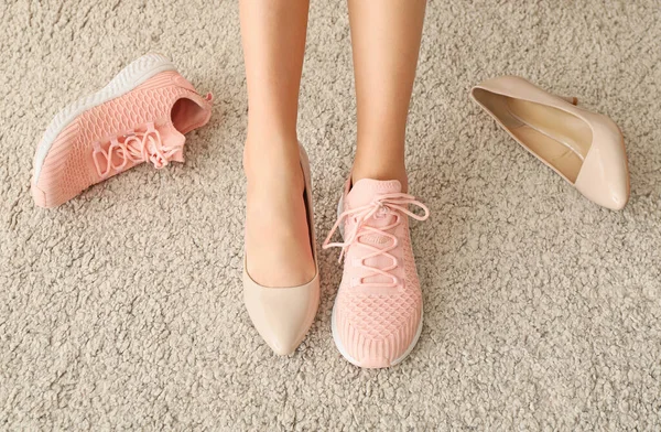 Jonge vrouw veranderende schoenen met hoge hakken voor comfortabele degenen thuis — Stockfoto