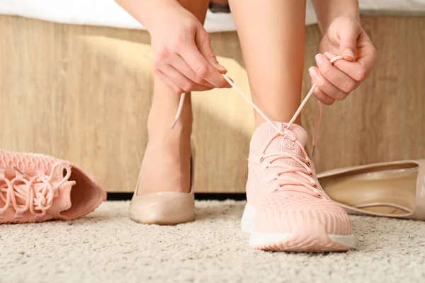 Jonge vrouw veranderende schoenen met hoge hakken voor comfortabele degenen thuis — Stockfoto