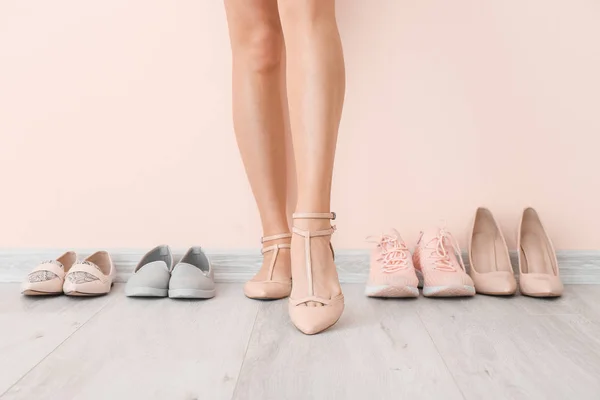 Mujer joven con diferentes zapatos elegantes cerca de la pared de luz — Foto de Stock