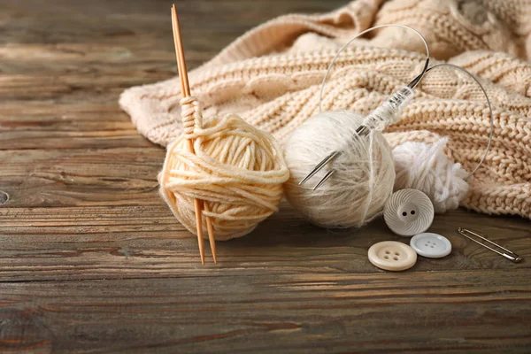 Knitted clothes, yarns and needles on wooden background — Stock Photo, Image