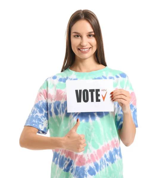 Young woman holding paper with text VOTE and showing thumb-up on white background — Stock Photo, Image