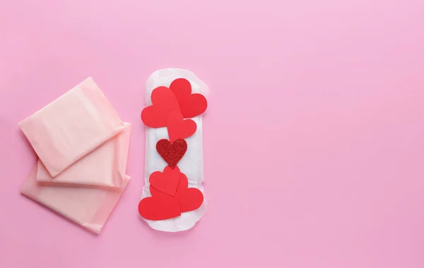 Menstrual pads with red paper hearts on color background — Stock Photo, Image