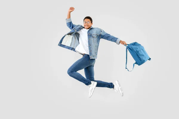 Jumping African-American teenager boy with backpack on white background — Stock Photo, Image