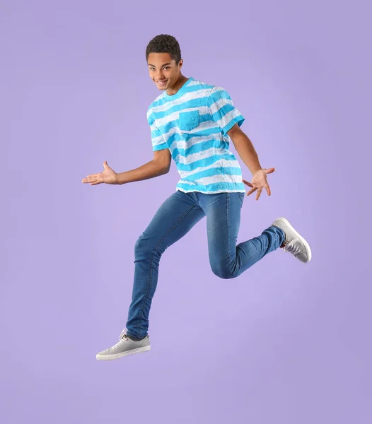 Jumping African-American teenager boy on color background — Stock Photo, Image